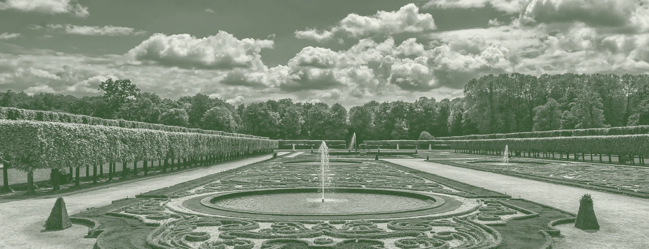 A formal parterre garden, hedges and planting receding to a tree line